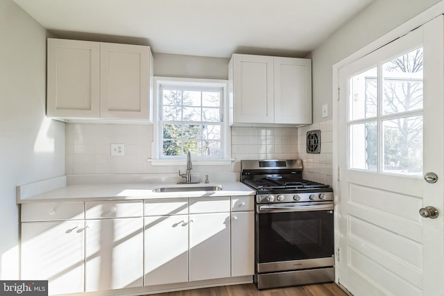 kitchen featuring gas stove, light countertops, a sink, and decorative backsplash