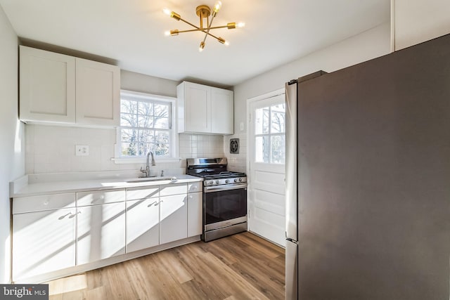 kitchen with stainless steel appliances, a sink, light countertops, tasteful backsplash, and plenty of natural light