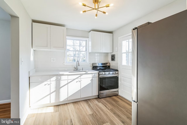 kitchen with light wood-style flooring, appliances with stainless steel finishes, backsplash, and a sink