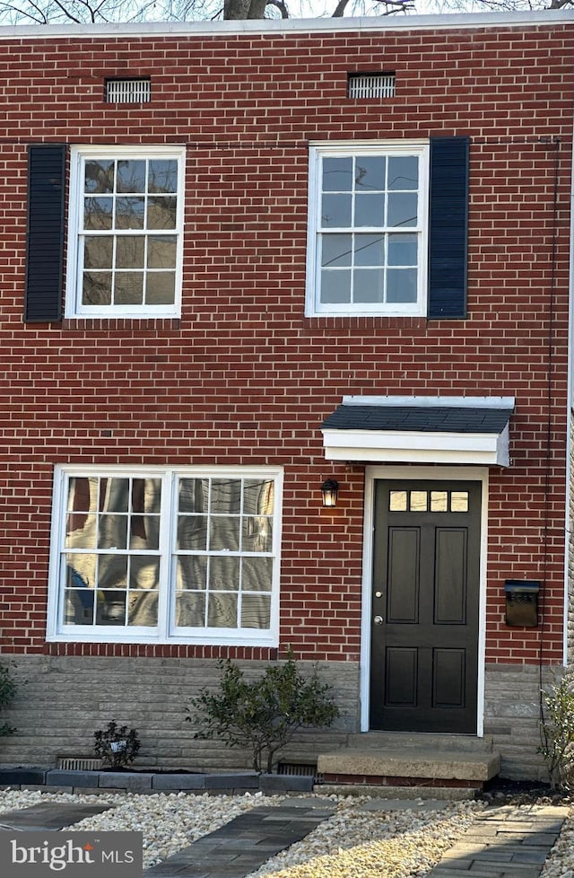 view of exterior entry featuring crawl space and brick siding