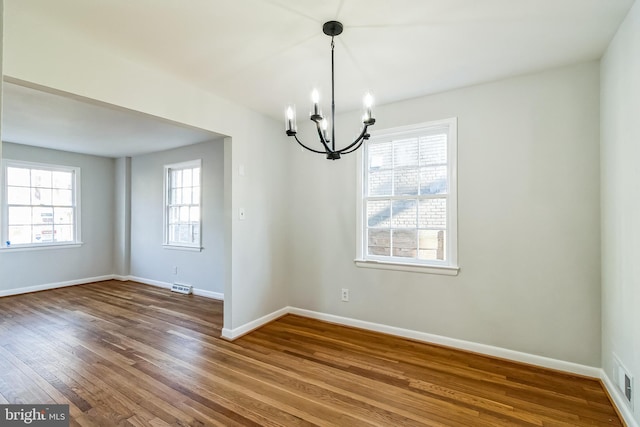 empty room with visible vents, baseboards, a chandelier, and dark wood-style flooring