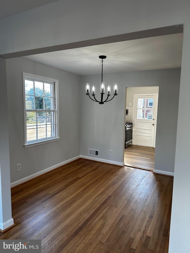 unfurnished dining area with dark wood-style floors, an inviting chandelier, visible vents, and baseboards