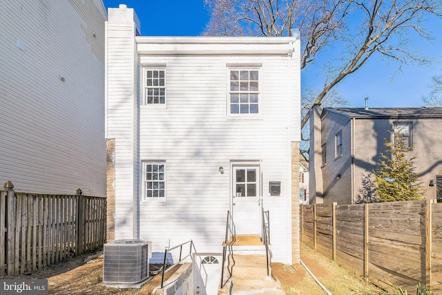 back of house featuring a fenced backyard, a chimney, and central AC unit