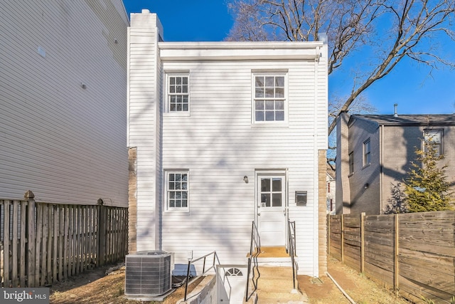 back of property with cooling unit and a fenced backyard