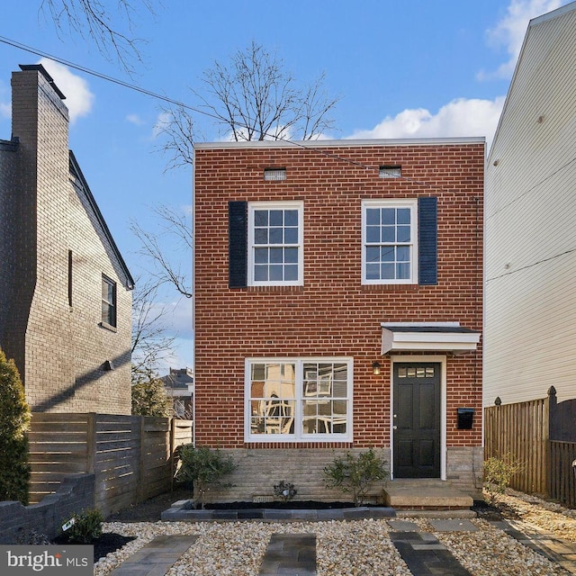 view of front of house featuring brick siding and fence