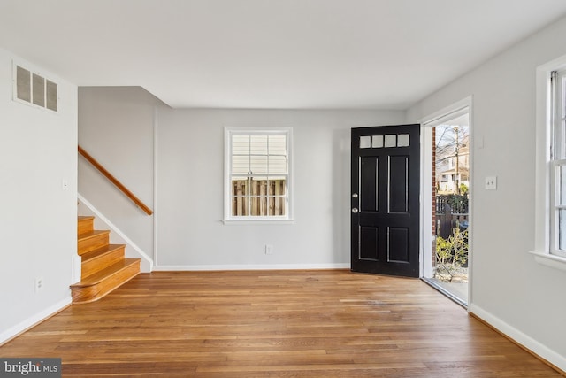 entrance foyer featuring a wealth of natural light, stairway, wood finished floors, and visible vents