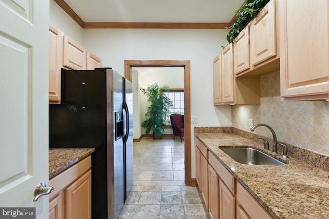 kitchen featuring light stone countertops, black fridge with ice dispenser, crown molding, and sink