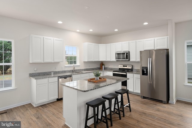 kitchen featuring stone counters, a healthy amount of sunlight, a center island, and stainless steel appliances