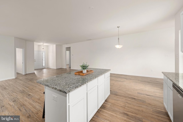 kitchen featuring white cabinetry, dishwasher, hanging light fixtures, light hardwood / wood-style floors, and stone countertops