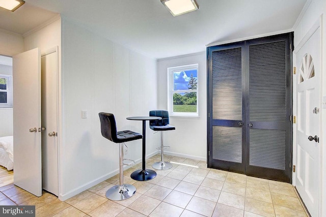 exercise room featuring crown molding and light tile patterned floors