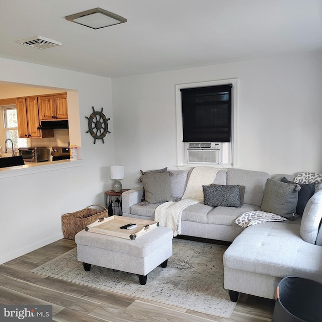 living room with hardwood / wood-style floors, cooling unit, and sink