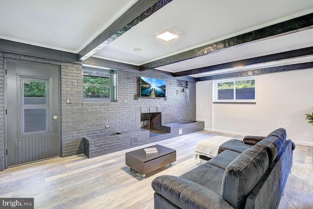 living room featuring a fireplace, beamed ceiling, brick wall, and hardwood / wood-style flooring