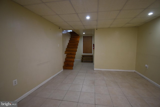 basement featuring a drop ceiling and light tile patterned floors