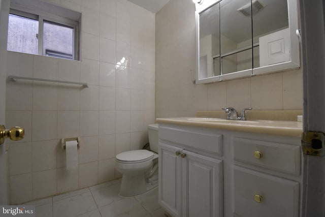 bathroom with vanity, toilet, and tile walls