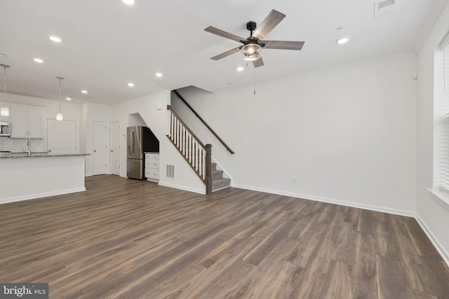 unfurnished living room with crown molding, ceiling fan, and dark hardwood / wood-style floors