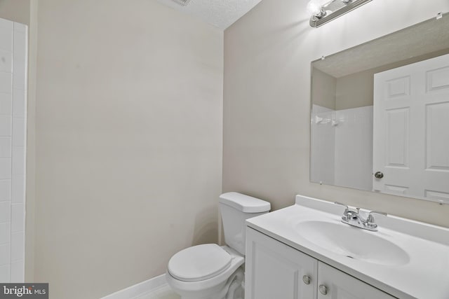 bathroom featuring vanity, a shower, toilet, and a textured ceiling