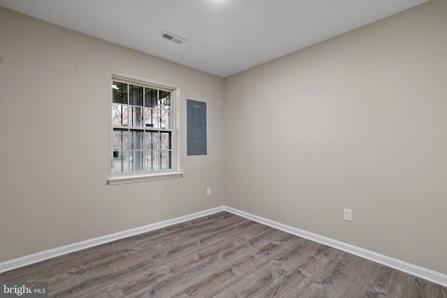 spare room featuring electric panel and light hardwood / wood-style flooring