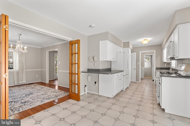 kitchen with white cabinetry, white appliances, and a chandelier