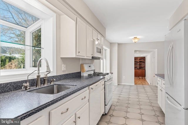 kitchen with white cabinetry, sink, and white appliances