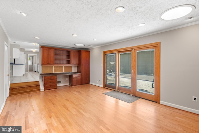 kitchen featuring light wood-type flooring, crown molding, built in desk, and a textured ceiling