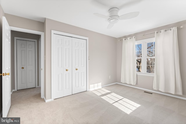 unfurnished bedroom featuring ceiling fan, light colored carpet, and a closet