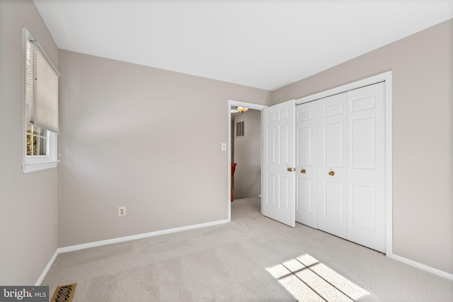 unfurnished bedroom featuring a closet and light carpet