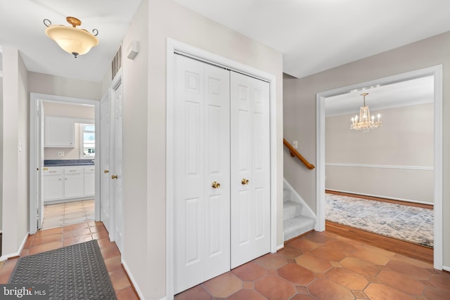 hall with tile patterned flooring and an inviting chandelier