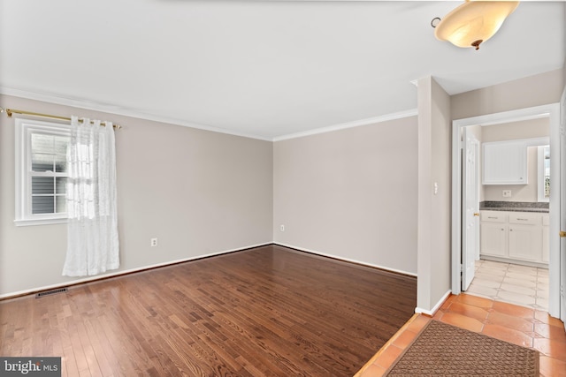 empty room featuring light wood-type flooring, plenty of natural light, and ornamental molding