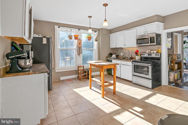 kitchen with white cabinets, decorative light fixtures, stainless steel appliances, and light tile patterned flooring