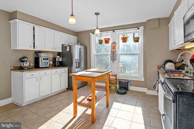 kitchen featuring white cabinets, light tile patterned floors, stainless steel appliances, and hanging light fixtures