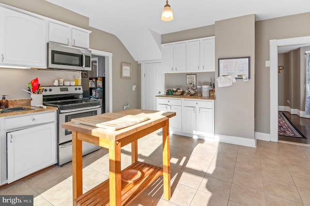 kitchen featuring white cabinets, lofted ceiling, light tile patterned floors, and stainless steel appliances