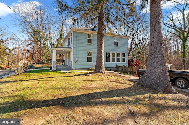 back of house with covered porch and a lawn