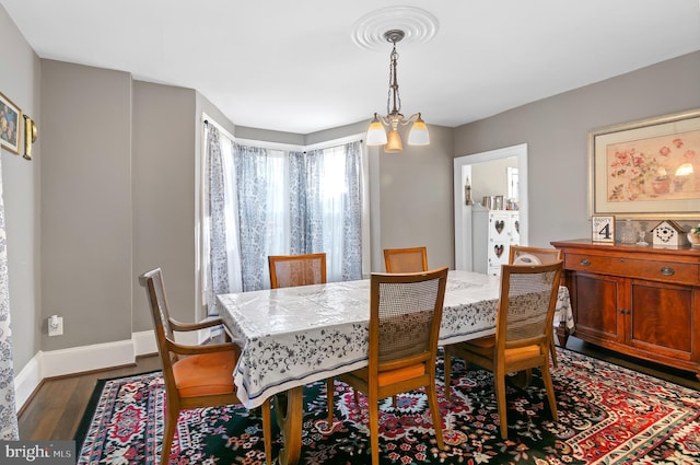 dining area with dark hardwood / wood-style flooring and an inviting chandelier