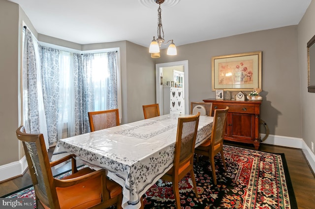 dining space with dark hardwood / wood-style flooring and an inviting chandelier