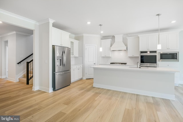 kitchen featuring appliances with stainless steel finishes, decorative light fixtures, light hardwood / wood-style floors, and custom exhaust hood