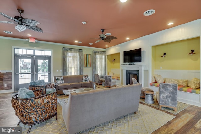 living room featuring ceiling fan, light wood-type flooring, crown molding, and french doors