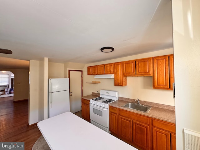 kitchen featuring white appliances, dark wood-type flooring, and sink