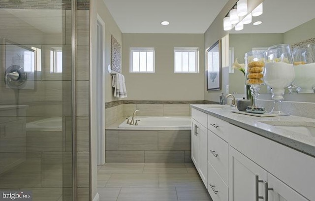 bathroom featuring plus walk in shower, vanity, and tile patterned flooring