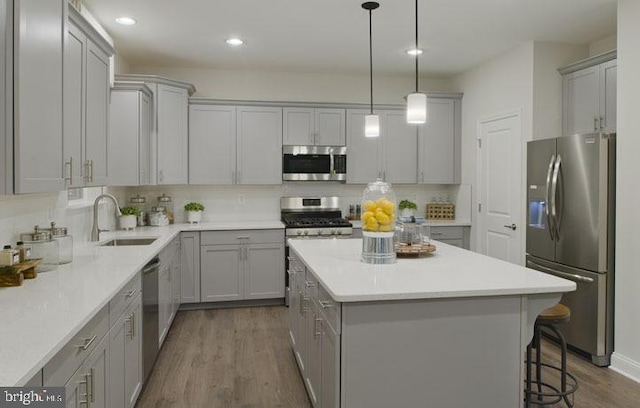 kitchen with gray cabinetry, sink, hardwood / wood-style flooring, a kitchen island, and stainless steel appliances