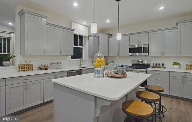 kitchen featuring appliances with stainless steel finishes, dark hardwood / wood-style flooring, sink, gray cabinets, and hanging light fixtures