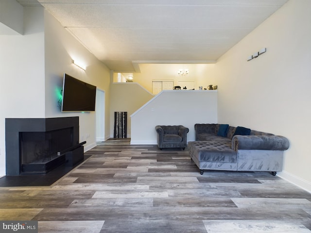 sitting room featuring an inviting chandelier, hardwood / wood-style floors, and a multi sided fireplace