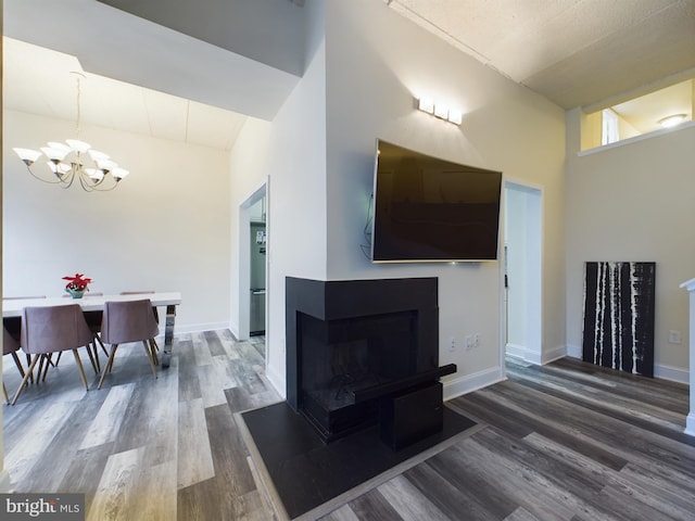 living room featuring a high ceiling, a multi sided fireplace, hardwood / wood-style floors, and a notable chandelier