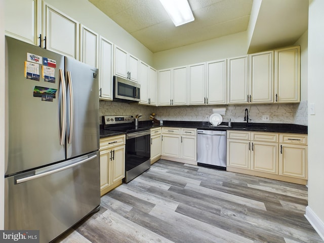 kitchen featuring tasteful backsplash, appliances with stainless steel finishes, sink, and light hardwood / wood-style floors