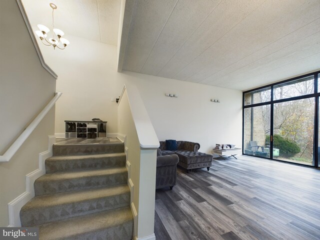 staircase featuring expansive windows, hardwood / wood-style floors, and a chandelier