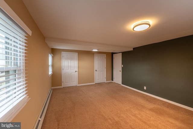 carpeted spare room featuring a baseboard radiator and a healthy amount of sunlight