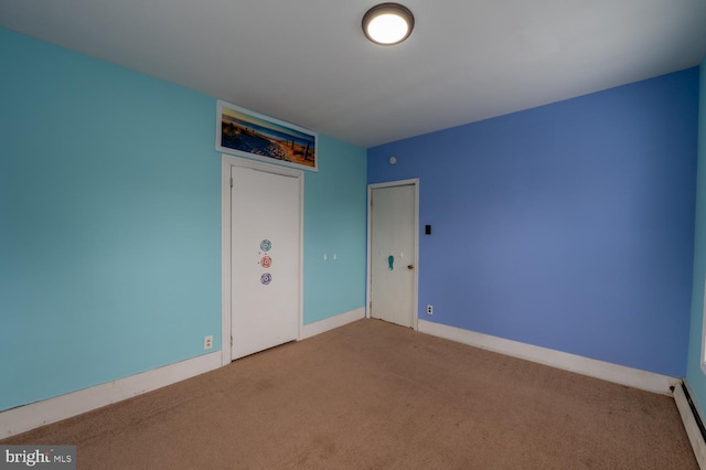 unfurnished bedroom with carpet floors and a baseboard heating unit