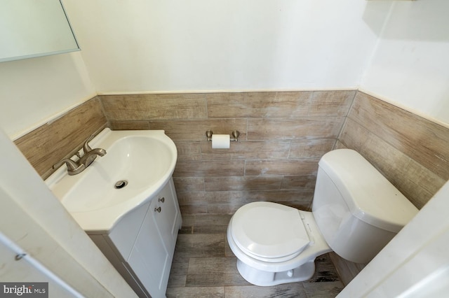 bathroom with vanity, toilet, and tile walls