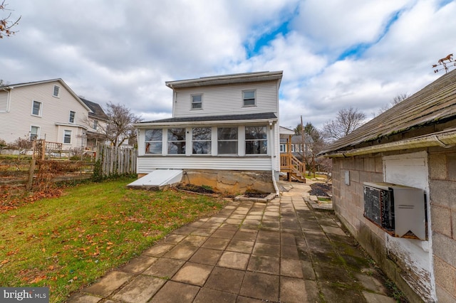 rear view of property with a yard, a patio area, and a sunroom