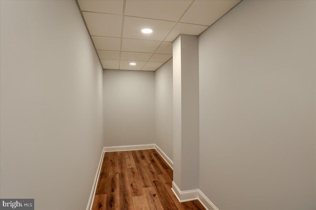 hall featuring a paneled ceiling, recessed lighting, baseboards, and wood finished floors