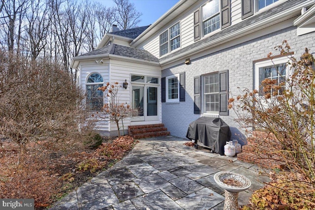 view of exterior entry featuring a patio area and brick siding